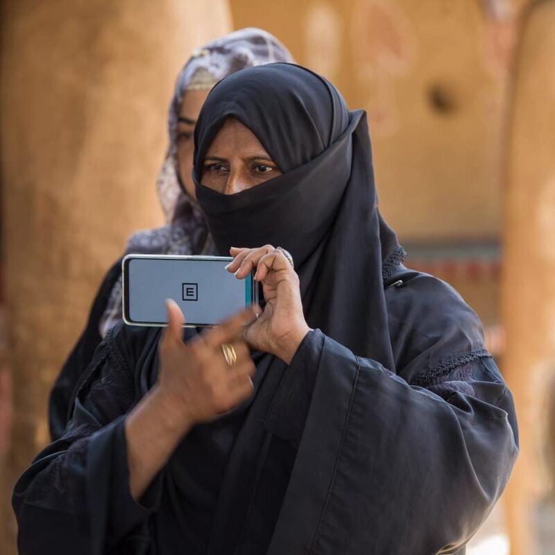 A Lady Health Worker conducts a vision screening using the Peek app in Pakistan. She holds up the phone showing the 'tumbling E'.