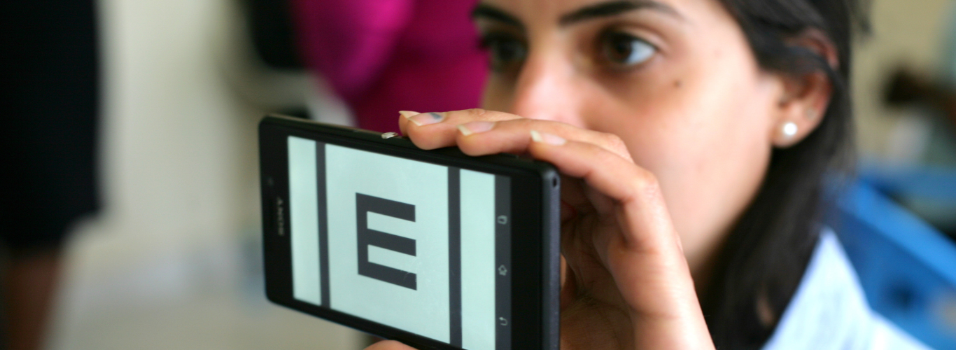 Person holding a phone showing the 'tumbling E' of the Peek Acuity smartphone-based vision test.