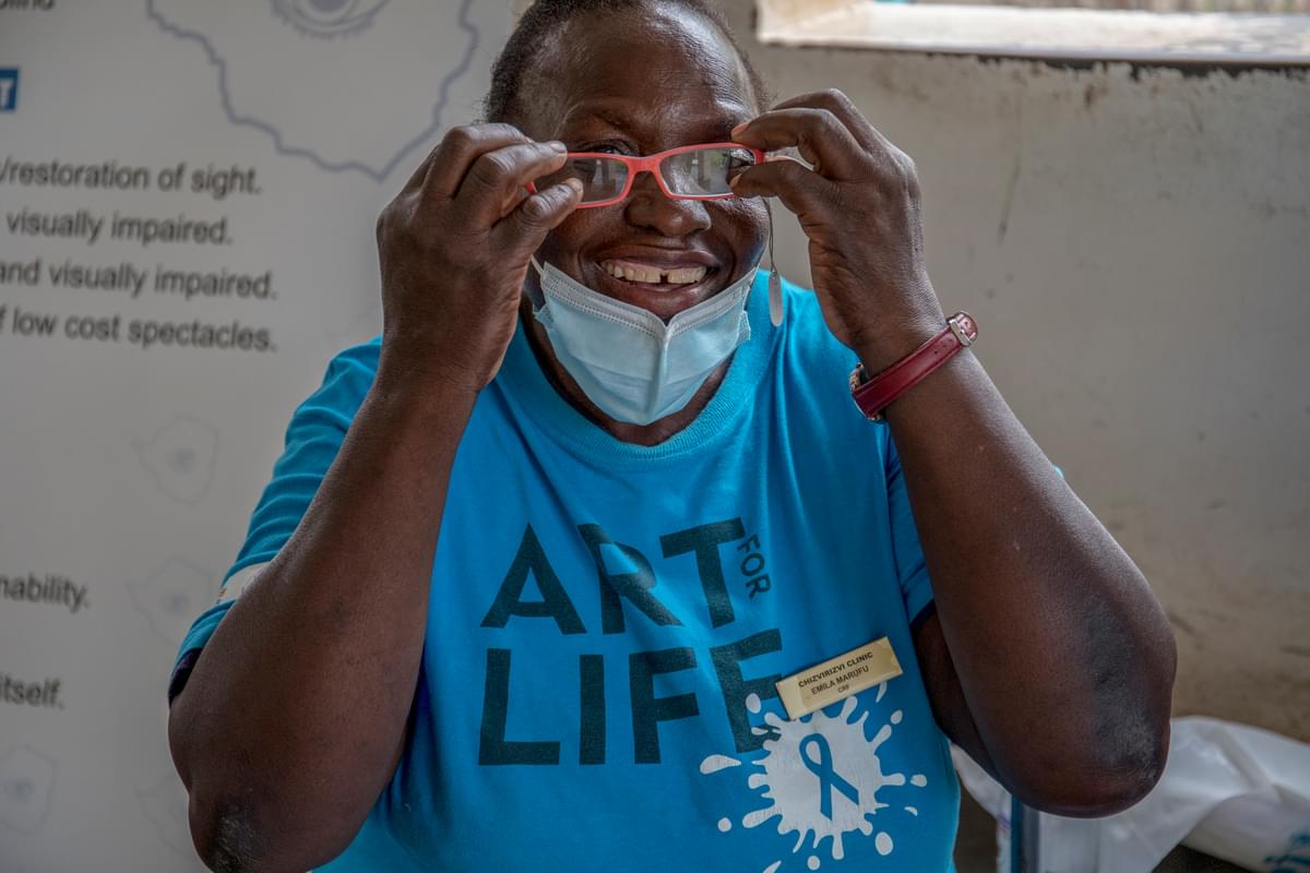 A woman smiles as she sees through glasses for the first time at a clinic in Zimbabwe.