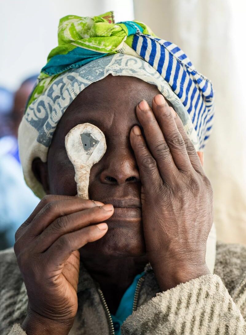 A Kenyan woman covers one eye as she has her sight tested by Peek after an eye operation.