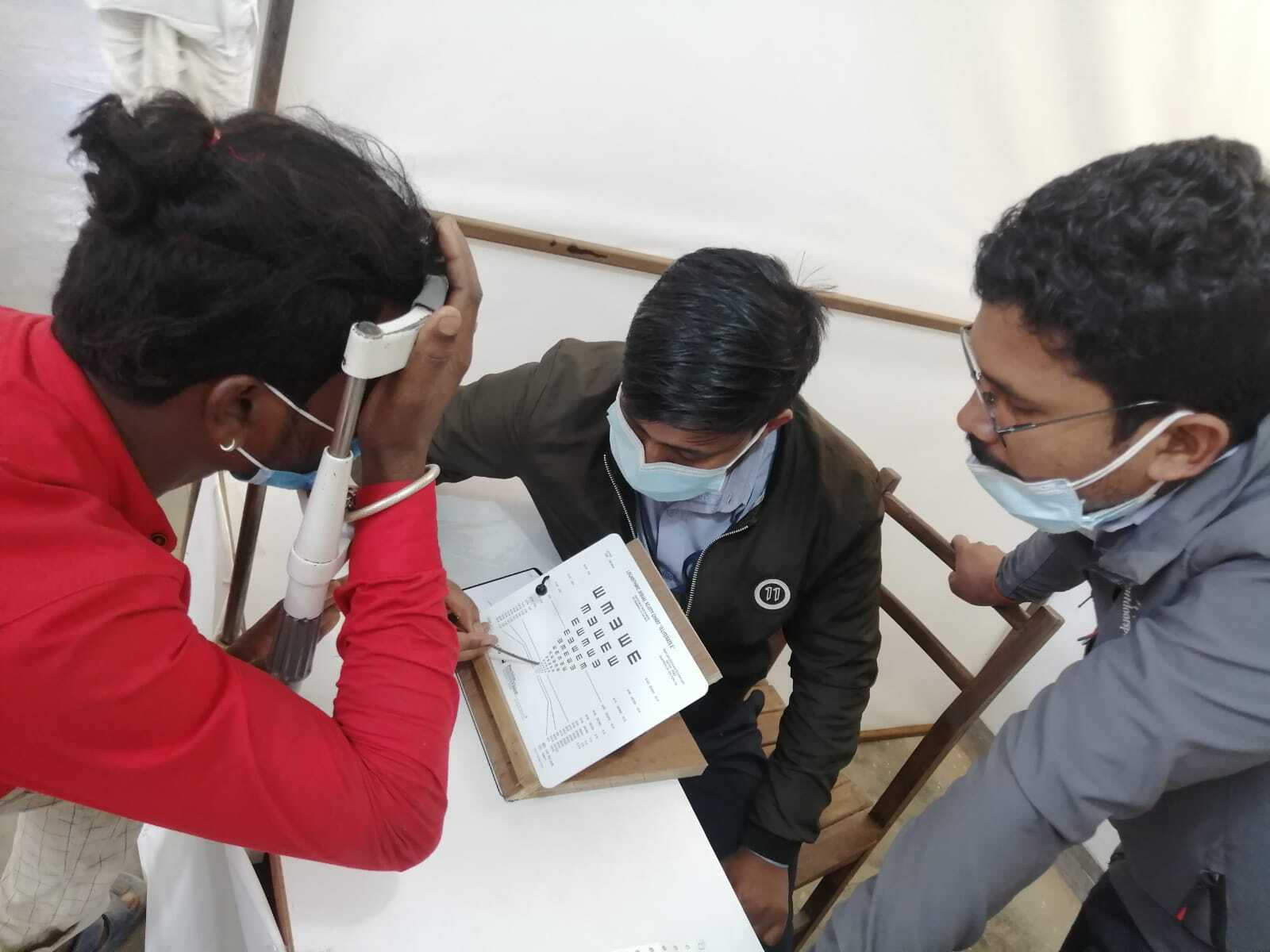 An individual undergoing an eye test, covering one eye as part of the examination process.
