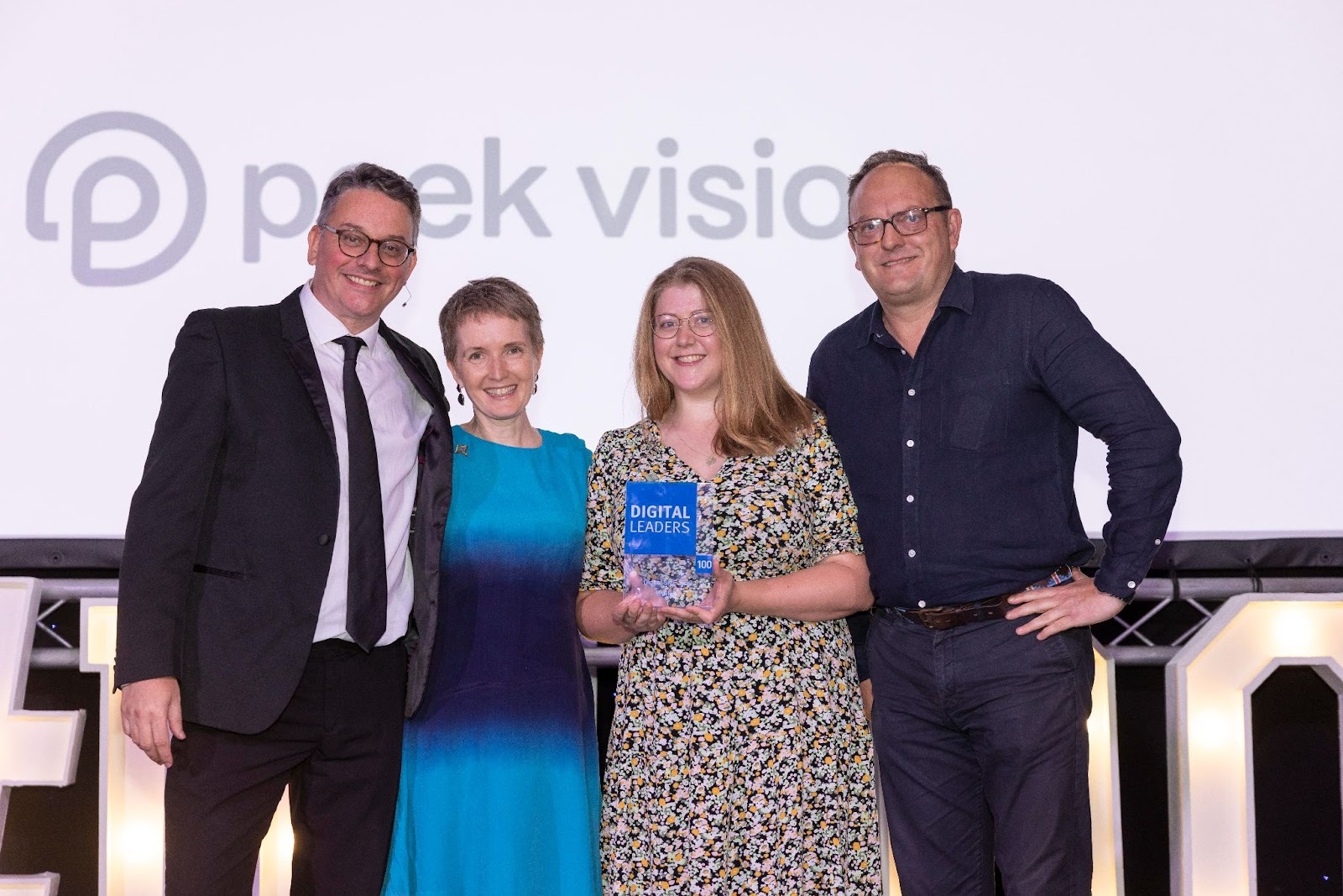 Jeanette McKenna and Marie-Claire Boyle from Peek Vision, positioned second and third from the left, at the Digital Leaders 100 award ceremony, accompanied by event host Alex Boardman and category sponsor Blaise Hamond, in a celebratory and prestigious setting.