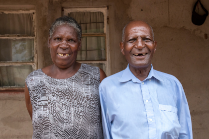 A married couple, James and Tembani smile outside of their rural Zimbabwean village home after James' received successful cataract surgery