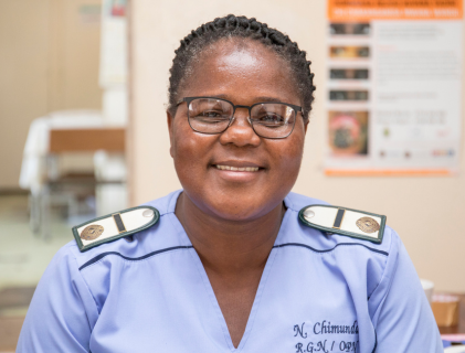 Nyengedzo Chimunda's headshot. She is wearing a healthcare workers' uniform and is sitting in on optical shop.