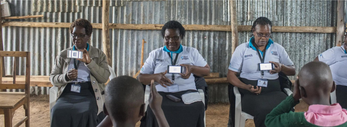 Three Kenyan women use the Peek Vision screening app to test the vision of children at a rural primary school in Kenya.
