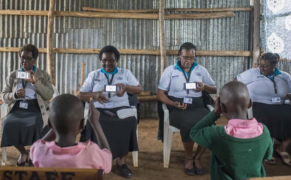 Four women conduct vision screening using the Peek app at a school in Kenya