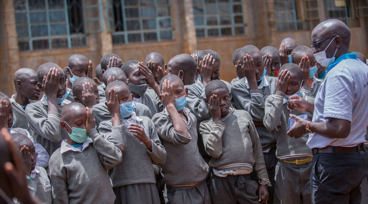 A group of Kenyan school children practise covering one eye ahead of having their vision screened.