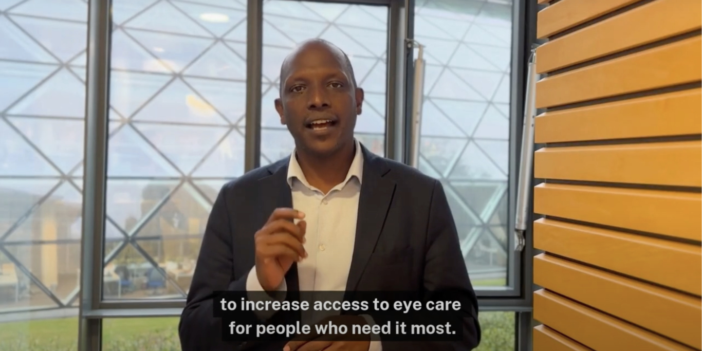 Still from a video of a man speaking facing the viewer. There is a caption saying "increase access to eye care for people who need it most".